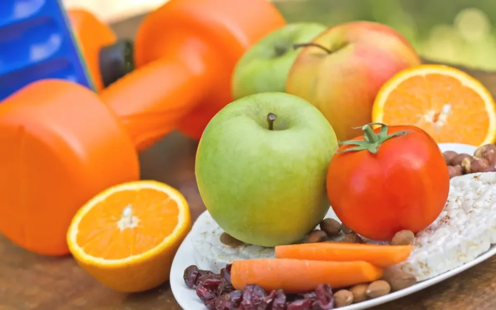 Emagrecer com Saúde: 5 Dicas Maravilhosas - Frutas, legumes e um peso de fazer ginástica em cima de uma mesa.