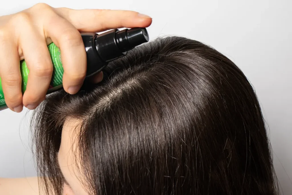 Mulher aplicando tônico capilar no cabelo e no couro cabeludo