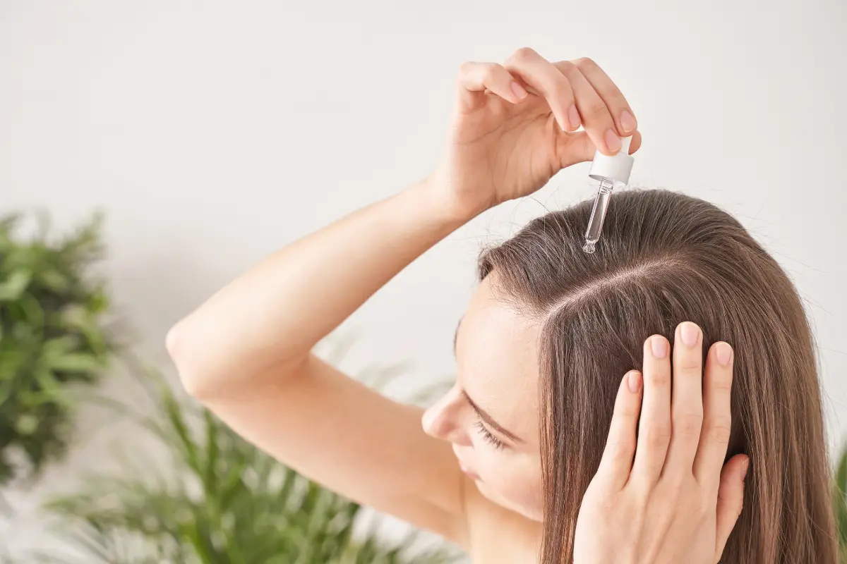 Tônico Capilar Cabelos mais Fortes e Saudáveis - Moça aplicando um tonico capilar no couro cabeludo com um conta-gotas