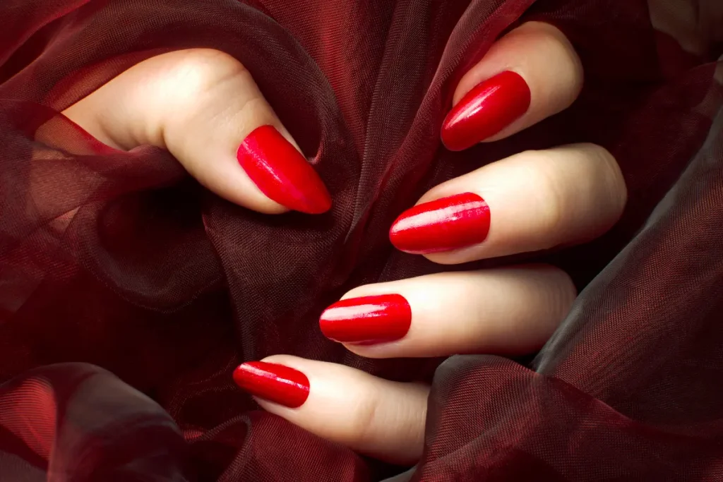 Mãos com unhas vermelhas segurando um tecido vermelho