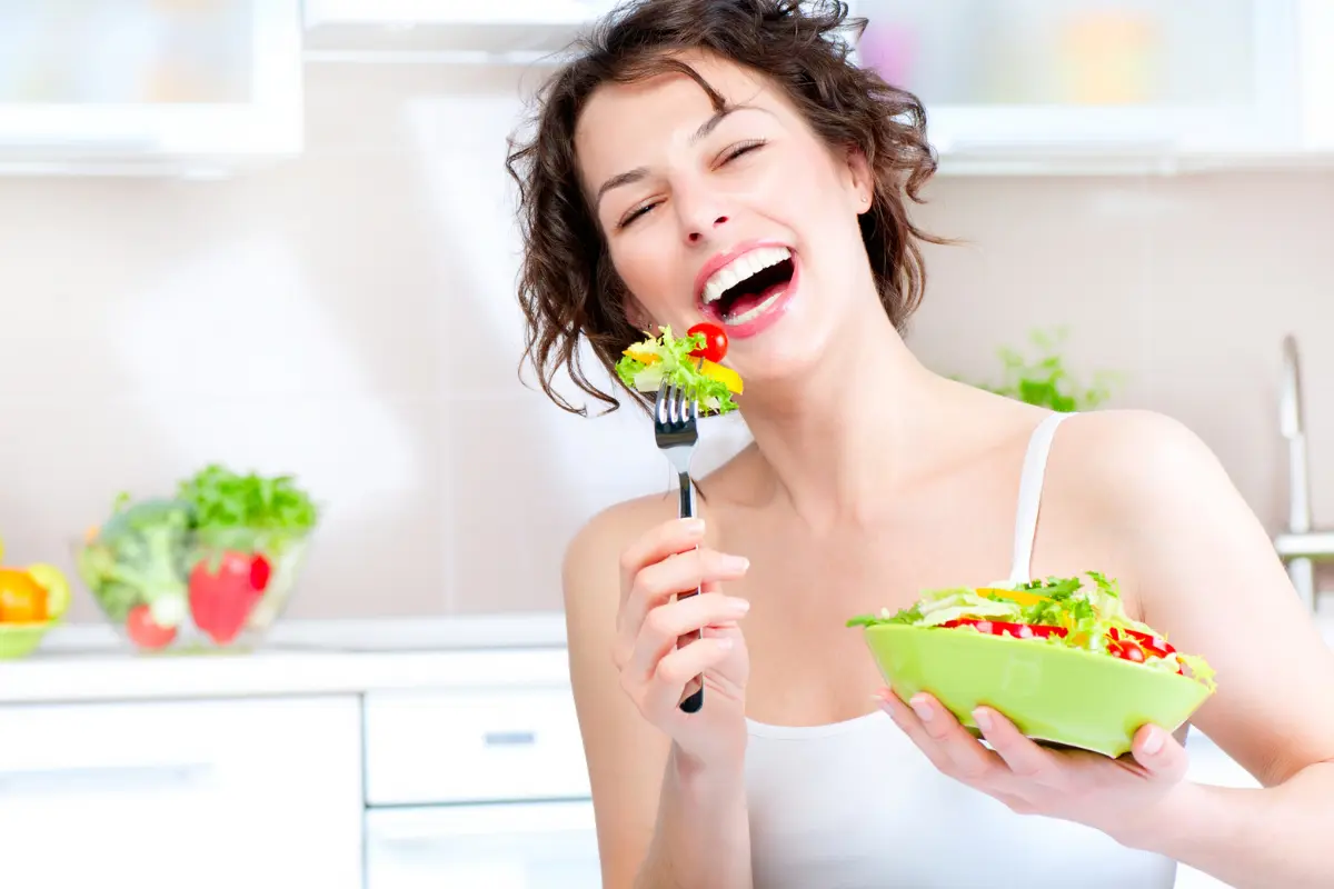 Verduras 5 Benefícios Essenciais - Mulher segurando um prato e comendo salada.
