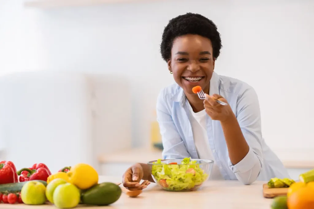 Mulher negra comendo salada