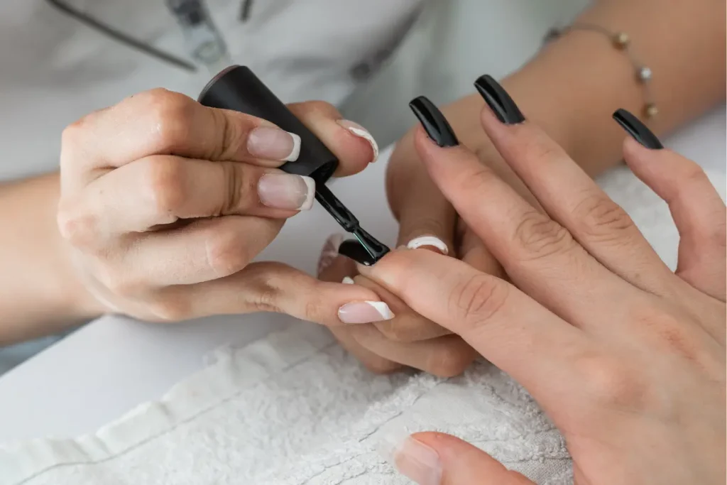 Manicure pintando as unhas da cliente de preto