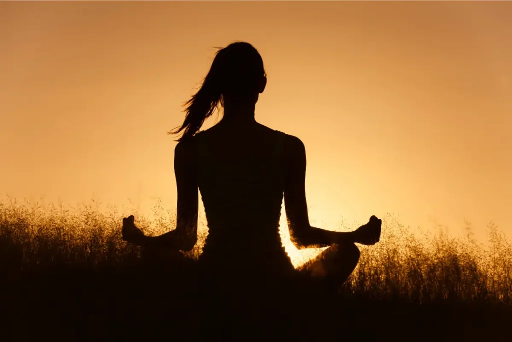 Mulher meditando ao pôr do sol