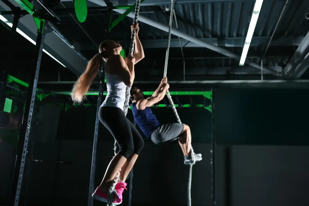 Homen e mulher subindo em cordas no CrossFit