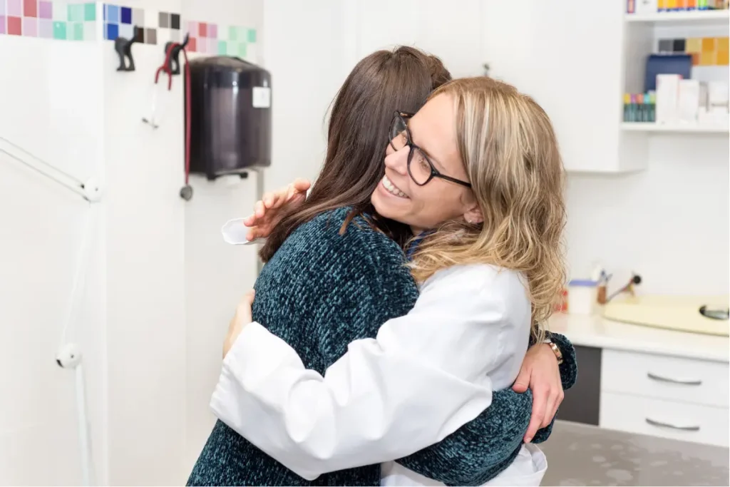 Uma médica feliz abraçando a paciente