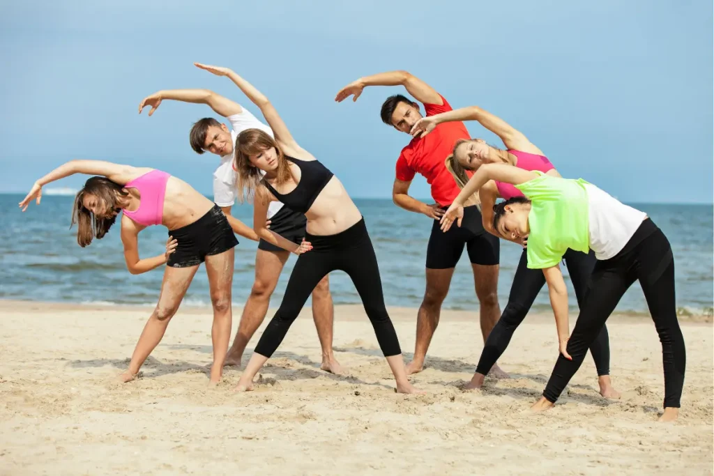 Grupo de pessoas fazendo exercício na areia da praia