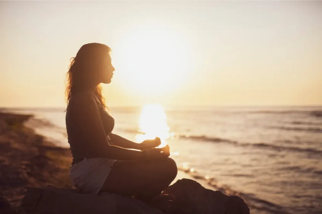 Mulher fazendo meditação na beira da praia