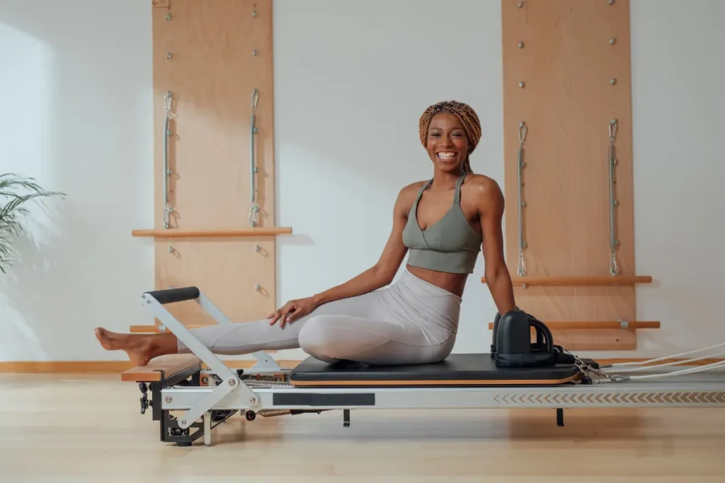 Mulher sorrindo sentada no aparelho Reformer