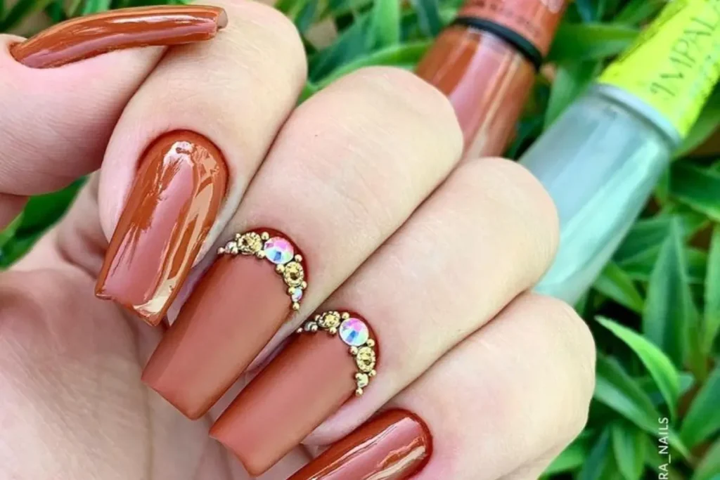 Unhas na cor de caramelo decoradas com predrarias