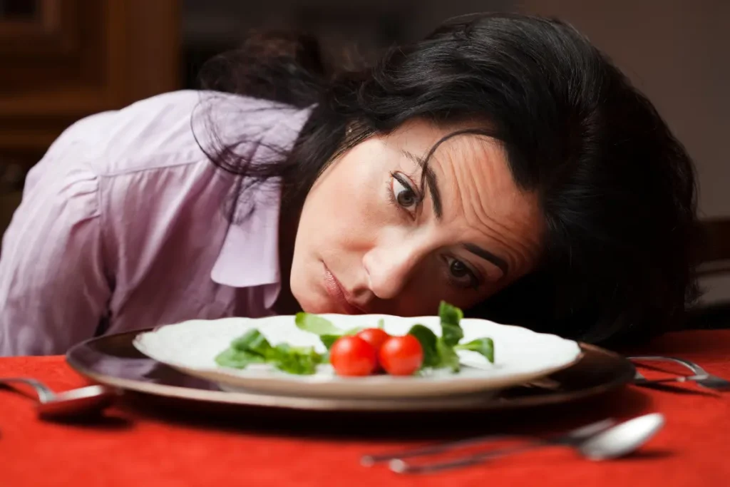 Mulher triste olhando para o seu prato de comida