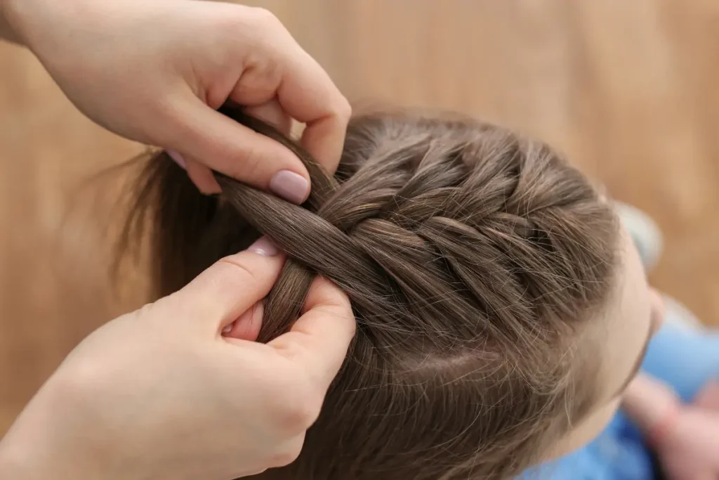 Cabelereira fazendo uma trança no cabelo da cliente