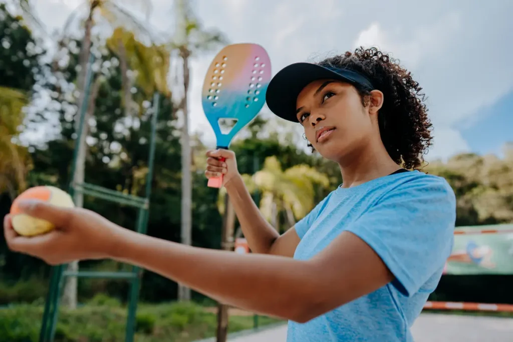 Mulher com bola e raquete de Beach Tennis em suas mãos