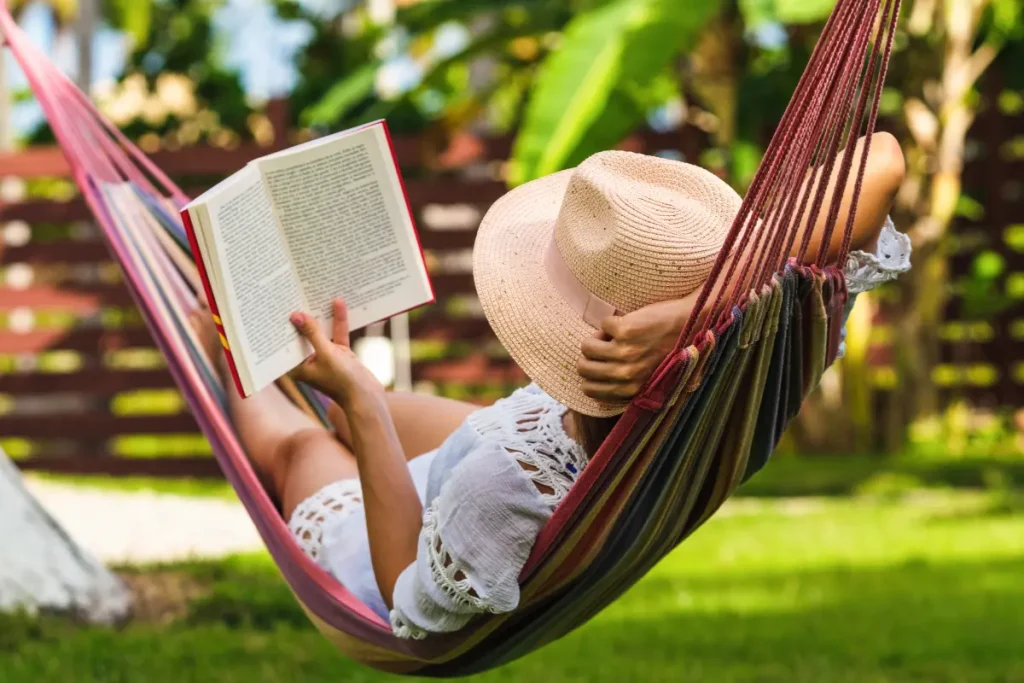 Mulher deitada numa rede lendo um livro