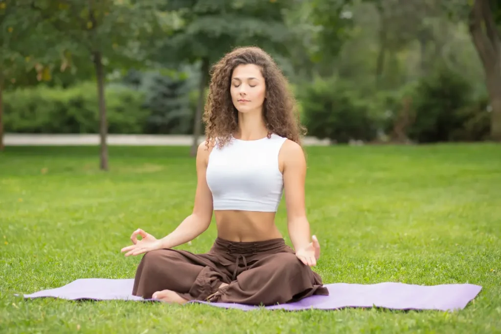 Mulher sentada na grama meditando