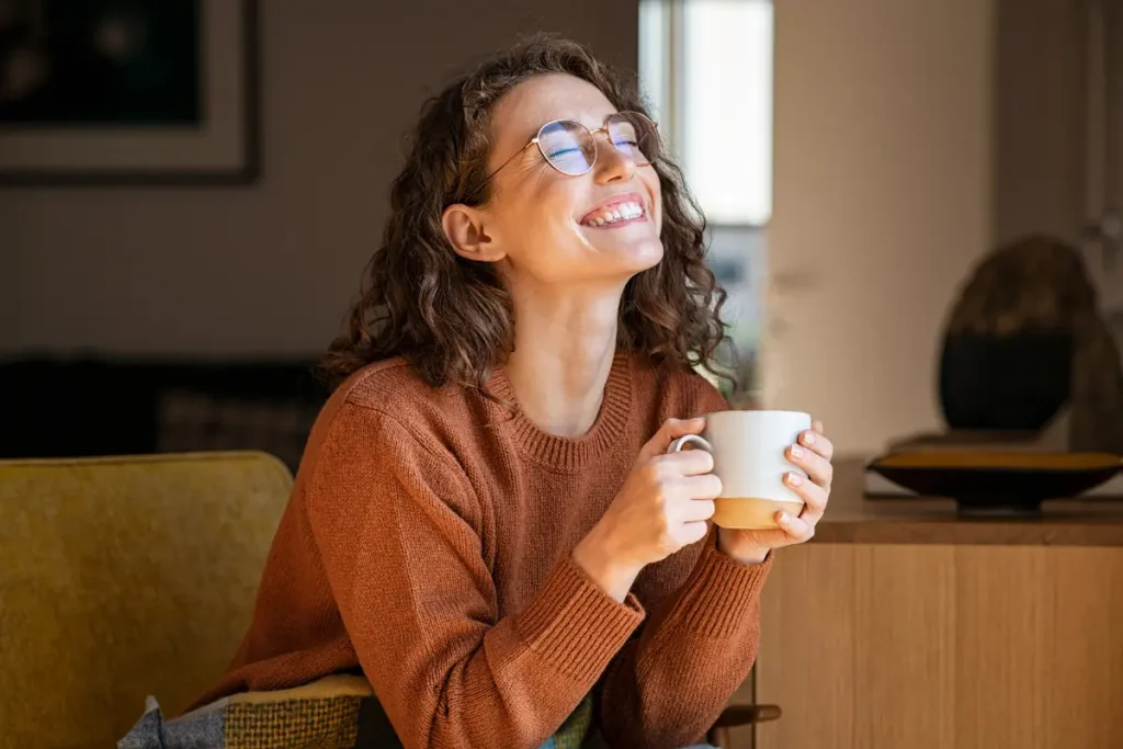 Mulher sorrindo, segurando uma xícara