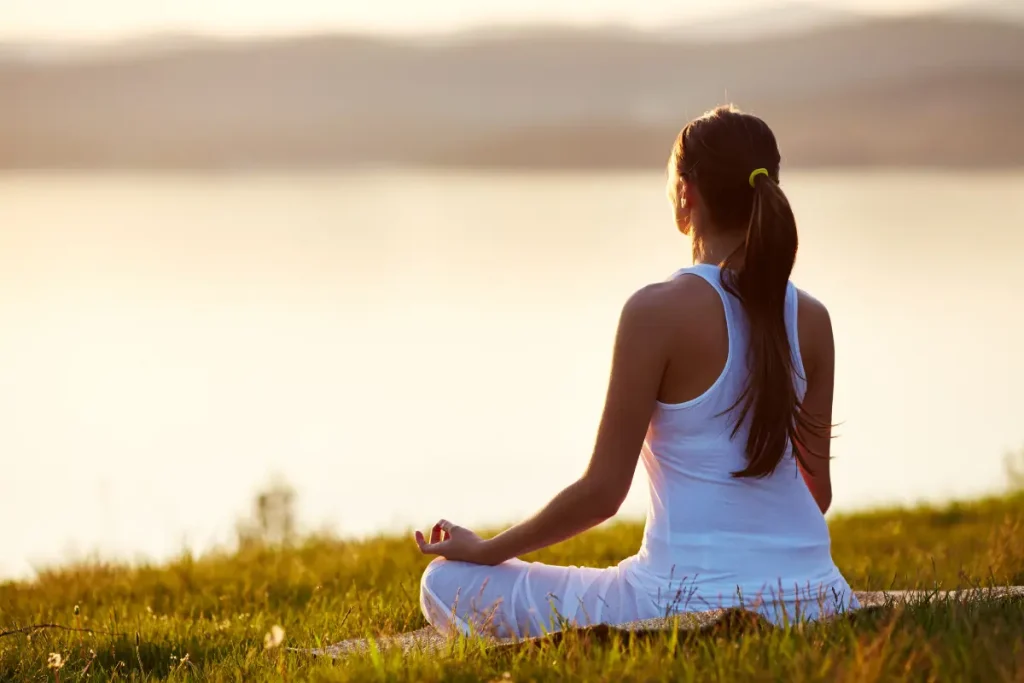 Moça meditando na beira de um lago