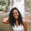 8 Hábitos Saudáveis Para Começar o Ano Com Mais Saúde - Mulher na beira de uma cachoeira sorrindo