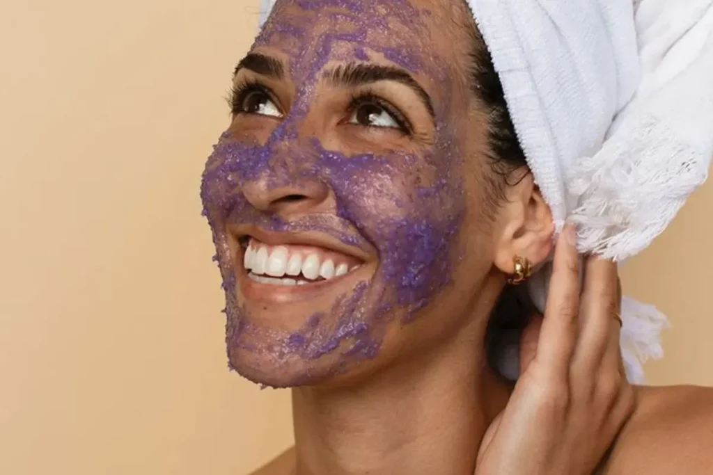 Mulher fazendo limpeza com esfoliante facial em seu rosto