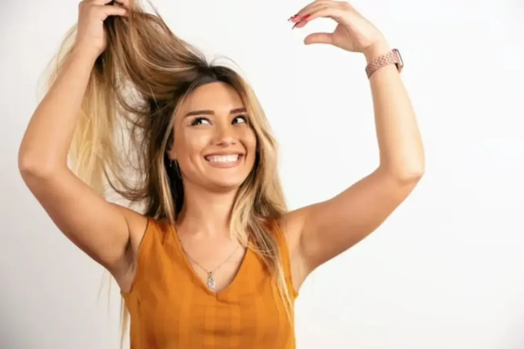 Mulher sorrindo e segurando o seu cabelo