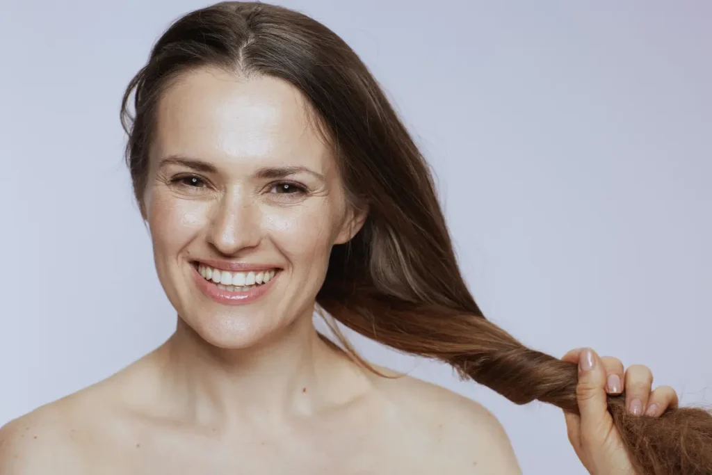 Mulher sorrindo segurando o cabelo