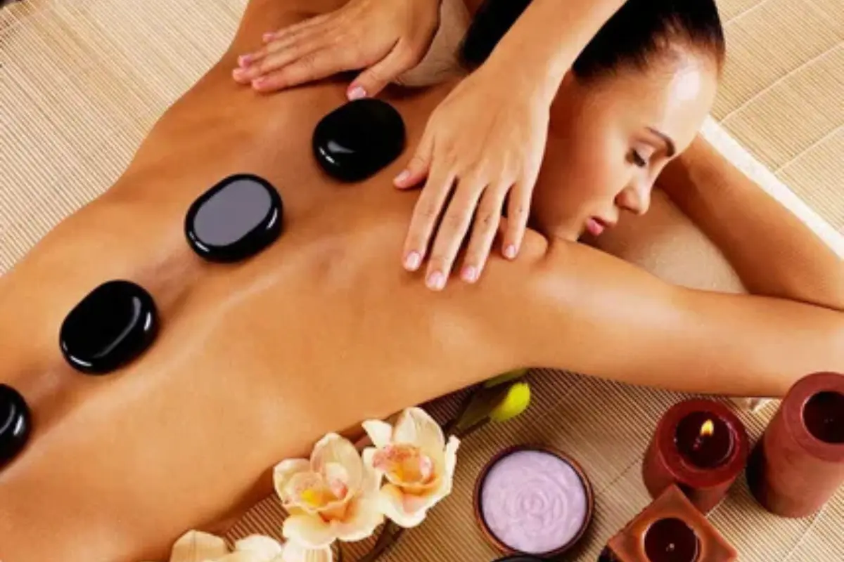 Massoterapia 7 Benefícios Importantes Para Seu Bem-Estar - Mulher numa sessão de massoterapia com pedras quentes