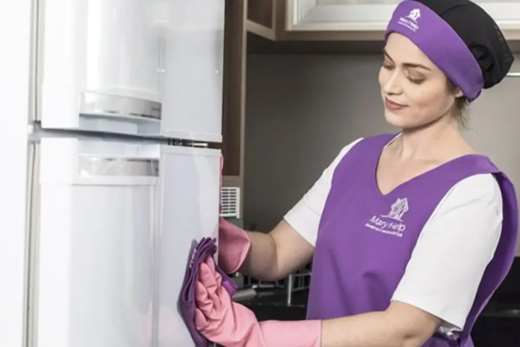 Mulher limpando uma geladeira e usando luvas nas mãos