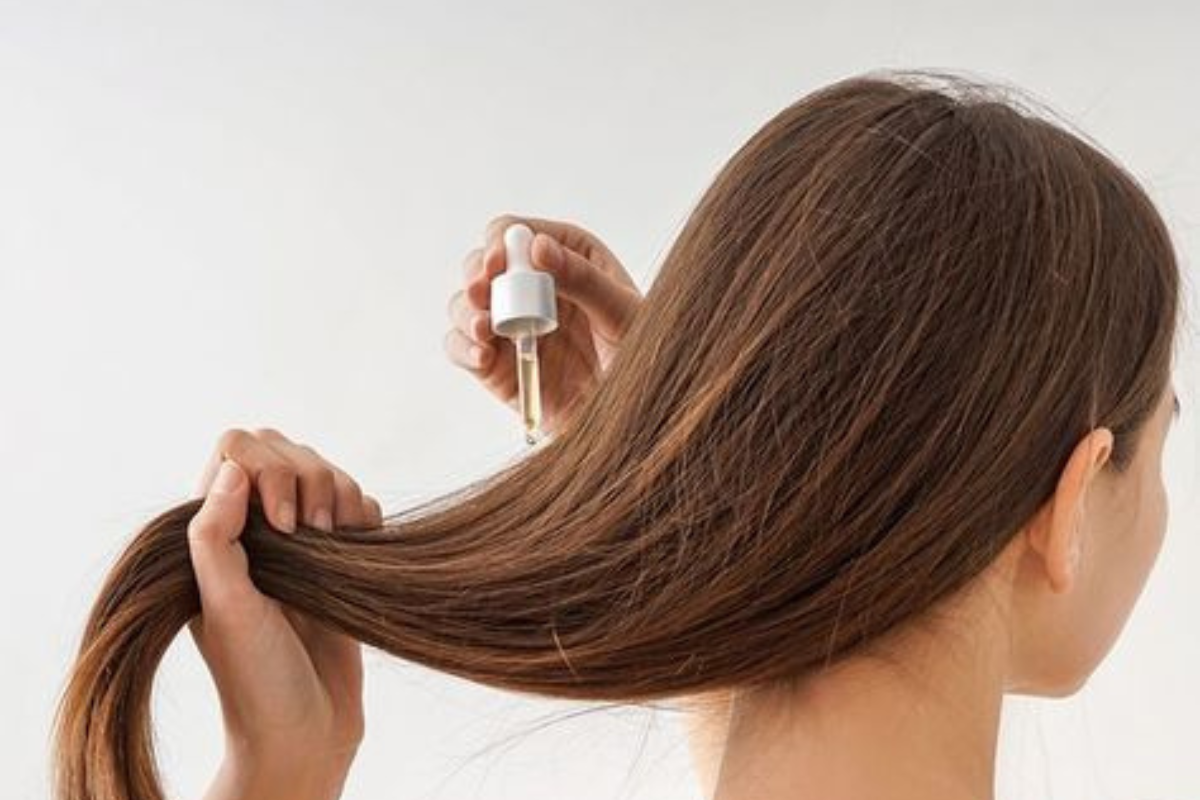 Jovem passando óleo capilar no cabelo