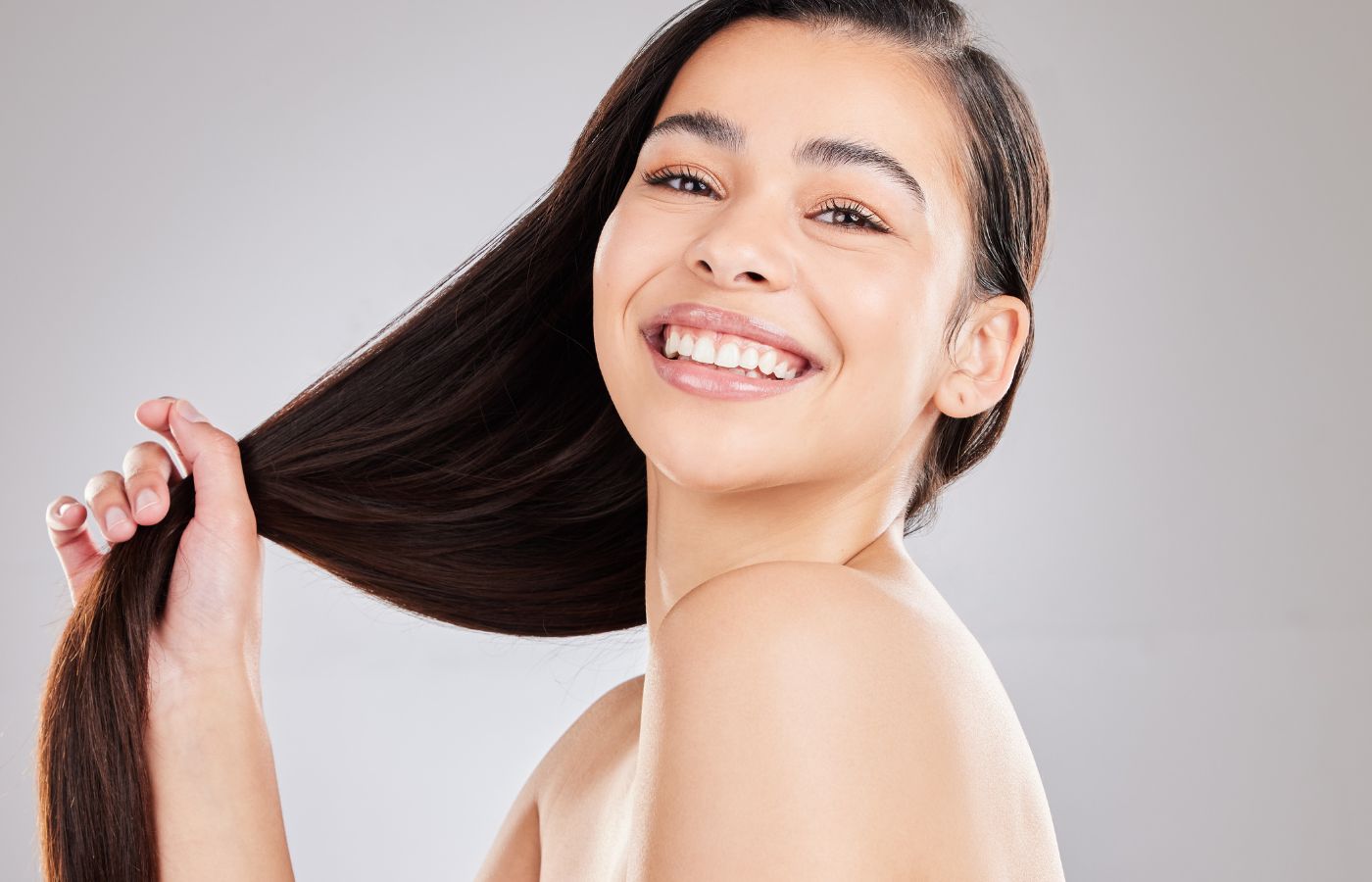 Jovem sorrindo segurando o cabelo