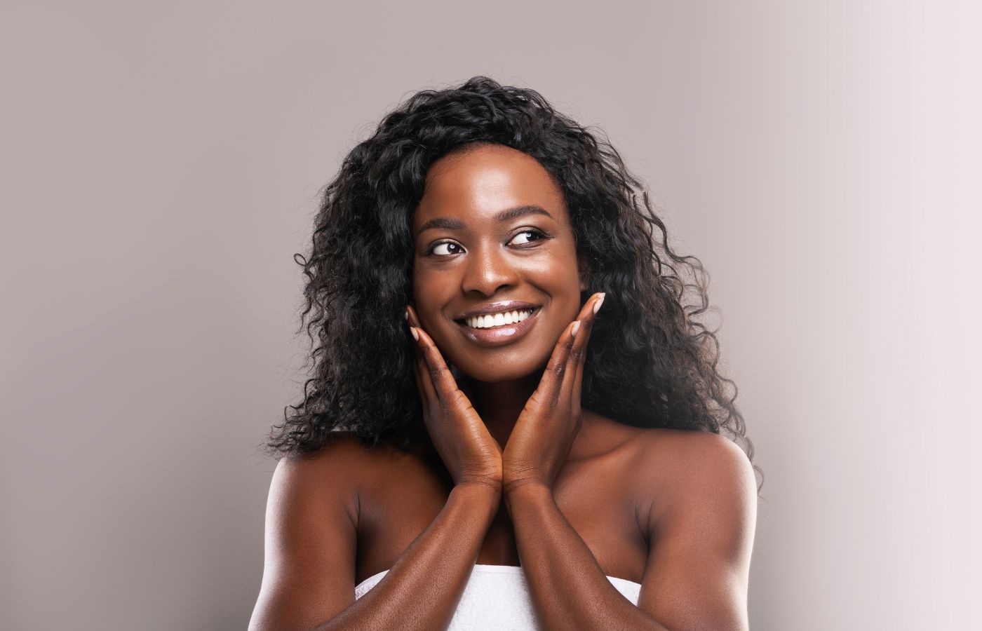 Mulher negra sorrindo com as mãos no rosto