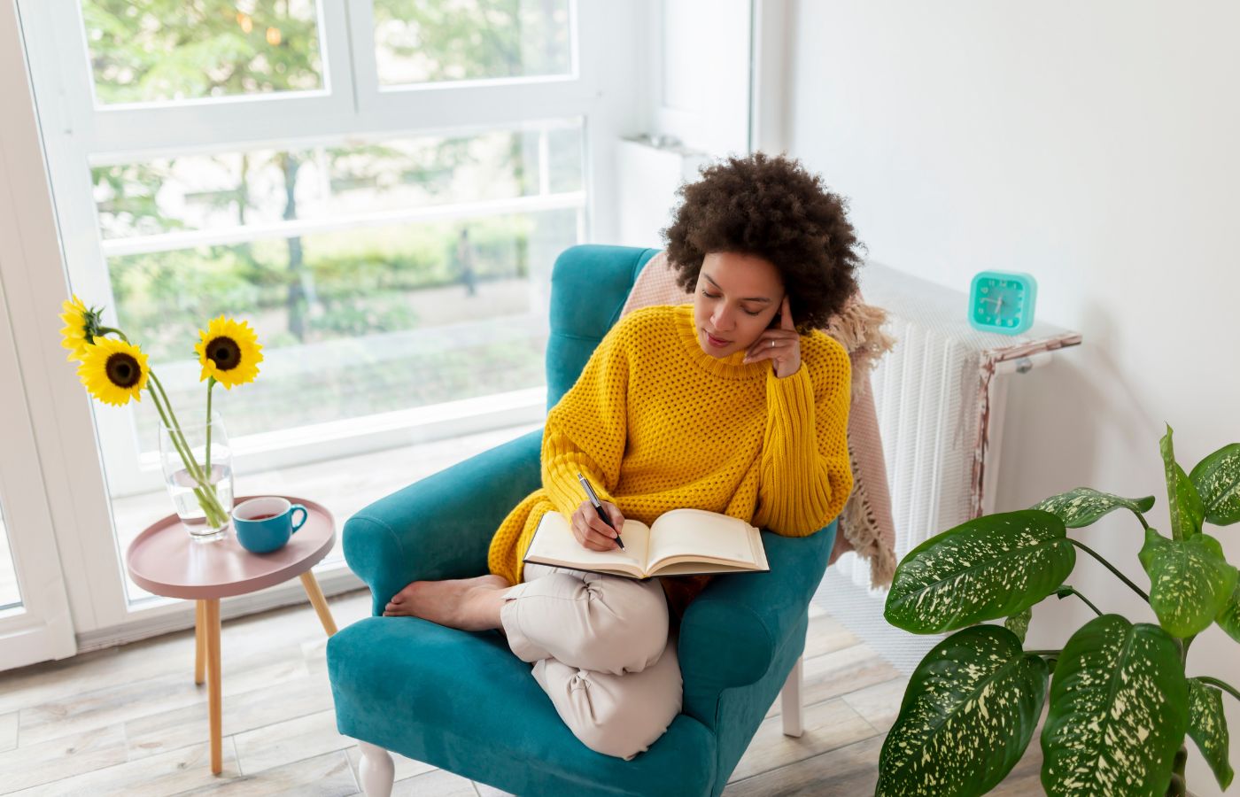 Mulher sentada numa poltrona escrevendo num diário