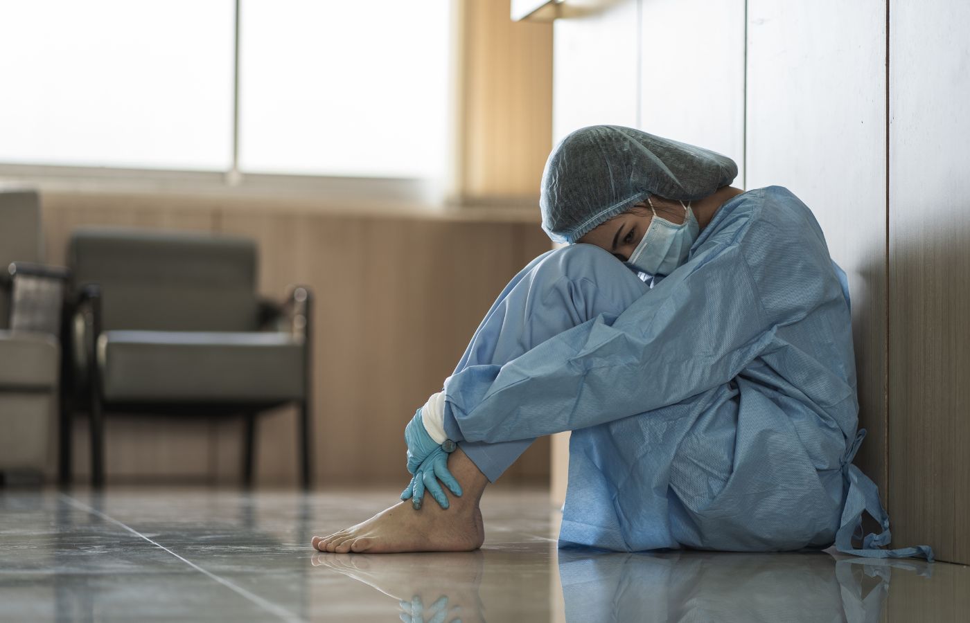 Médica triste sentada no chão